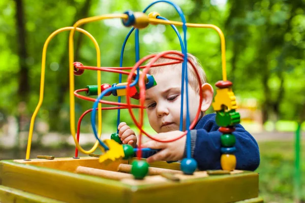 Menino brinca com um brinquedo lógico multicolorido — Fotografia de Stock