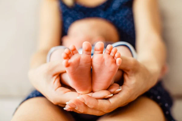 Mãe segura pequenos pés de bebê recém-nascido — Fotografia de Stock