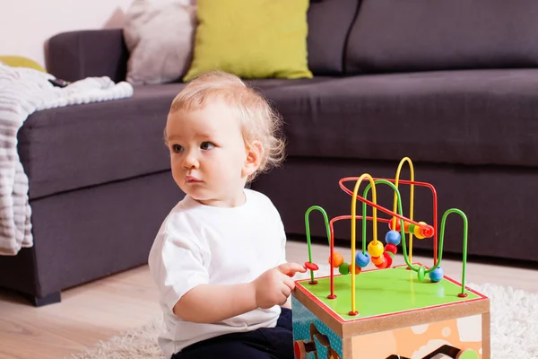 Bebé niño jugando en interiores con juguete sentado en una alfombra suave — Foto de Stock