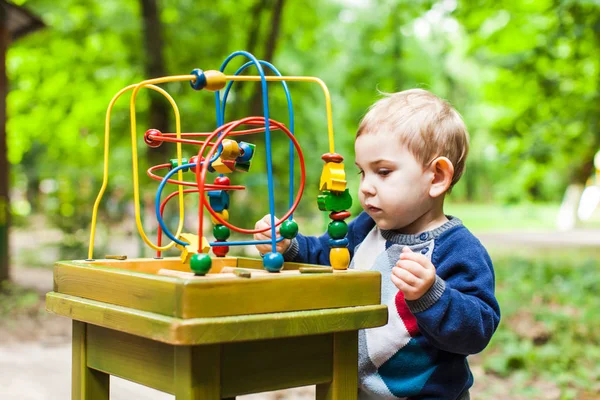 Chico juega con un juguete lógico multicolor — Foto de Stock