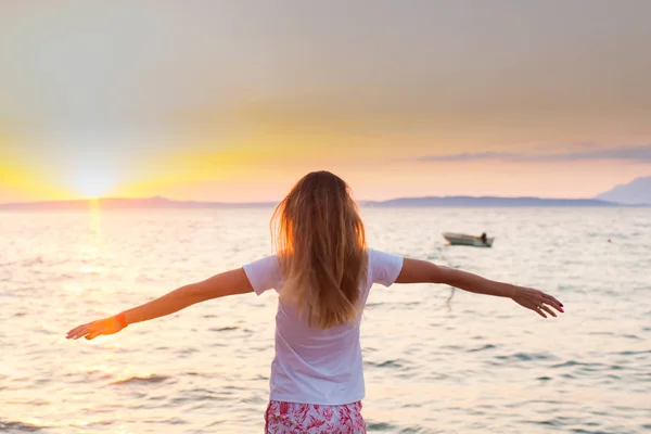 Joven pelo largo rubia frente al amanecer en el mar —  Fotos de Stock