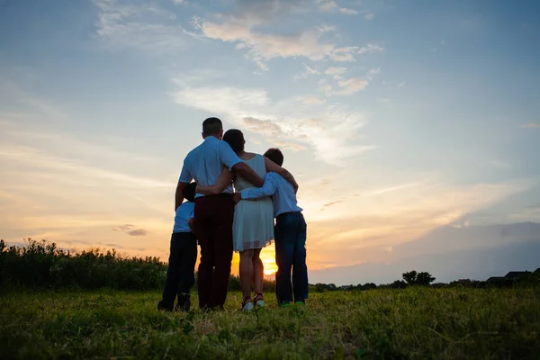 Família feliz no fundo do pôr do sol — Fotografia de Stock