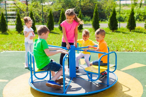 Die Kinder drehen abwechselnd das Karussell — Stockfoto