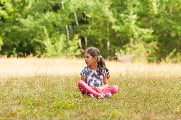 Lovely little six-year girl sitting on grass — Stock Photo, Image