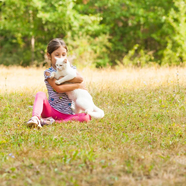 Liebliches Mädchen umarmt ihre weiße Hauskatze — Stockfoto