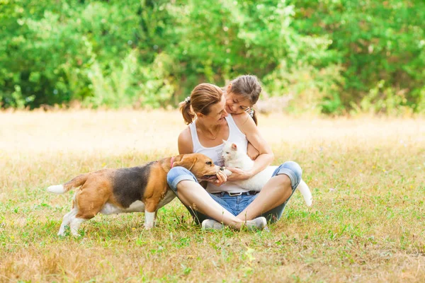 Junge Mutter und ihre Tochter spielen mit Hund und Katze — Stockfoto