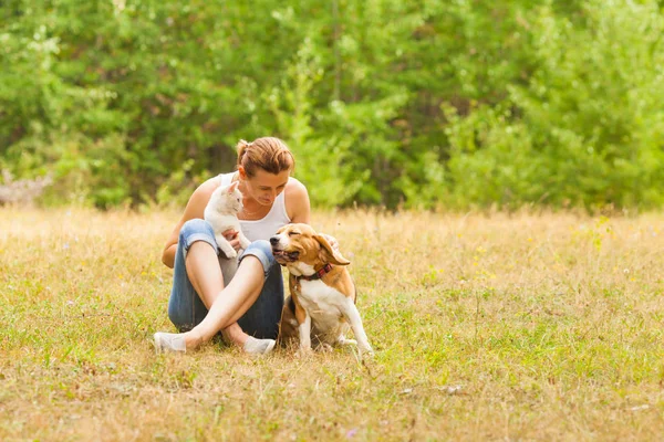 Dierenvriend vrouw dierenvriend zittend op het gras met haar huisdieren — Stockfoto