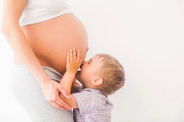 小さな男の子のお母さんの妊娠中の腹にキスします。 — ストック写真