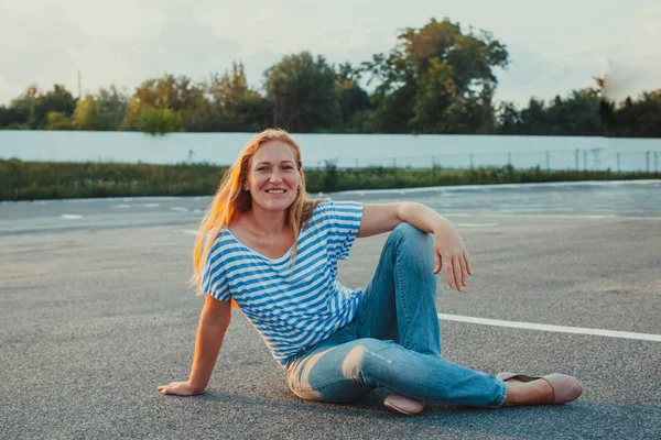 Jonge vrouw aanbrengen op asfalt camera kijken — Stockfoto