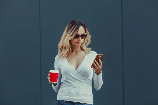 Kobieta z filiżanki kawy czerwony i smartphone — Zdjęcie stockowe