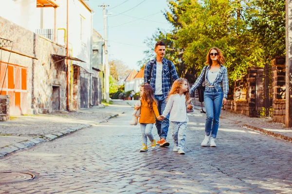 Twee meisjes lopen met hun vader en moeder — Stockfoto