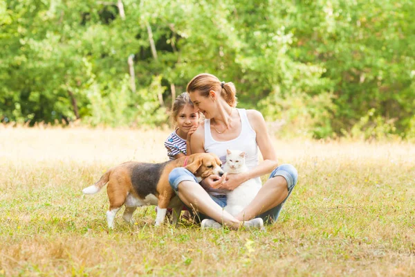 Bedårande par dotter och mamma sitter på ett gräs med sina husdjur — Stockfoto