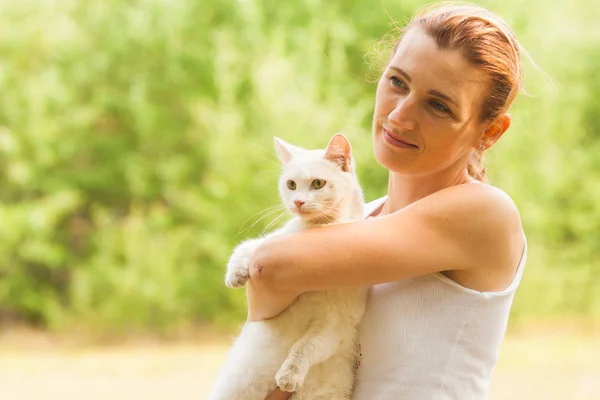Frau hält weiße Katze im Sommerpark — Stockfoto