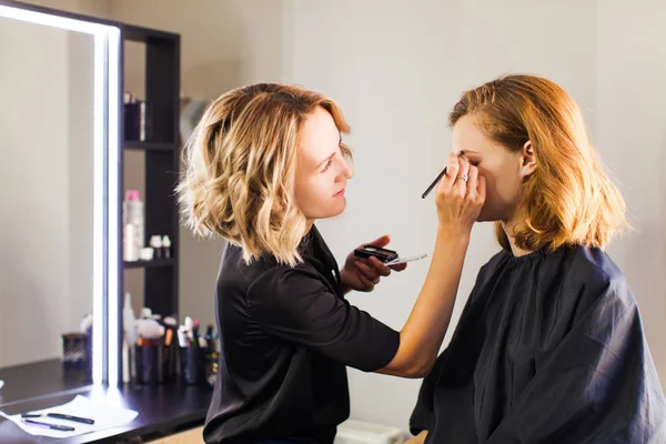 Stylist maakt jong meisje professionele make-up — Stockfoto