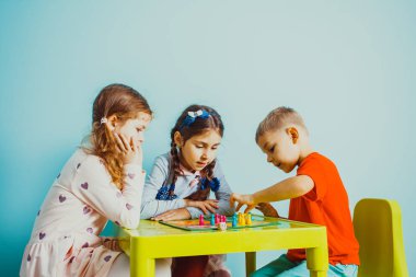 Birlikte masa etrafında oturup oynayan çocuklar