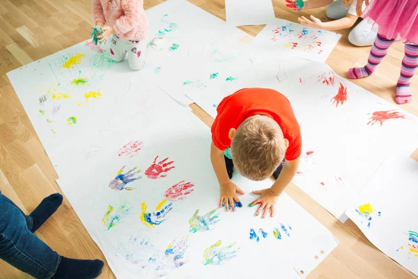 Menino fazendo impressões coloridas de suas palmas — Fotografia de Stock