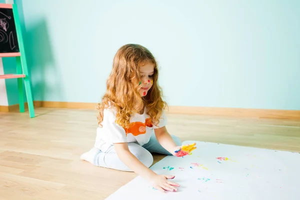 Charmante petite fille peinture à l'aide de ses doigts tout en étant assis sur le sol — Photo