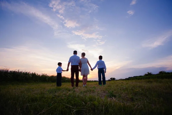 Happy family on the background of the sunset — Stock Photo, Image