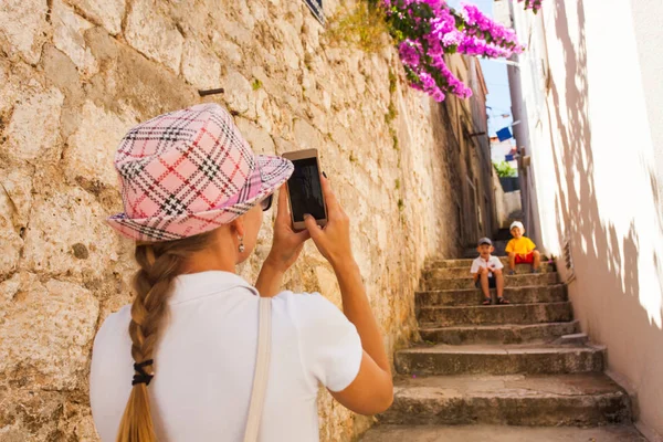 Mulher atraente fotografar seus filhos na rua antiga estreita — Fotografia de Stock