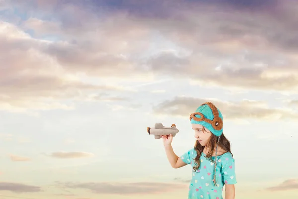 Hübsches Mädchen blickt auf Spielzeugflugzeug in ihren Armen — Stockfoto
