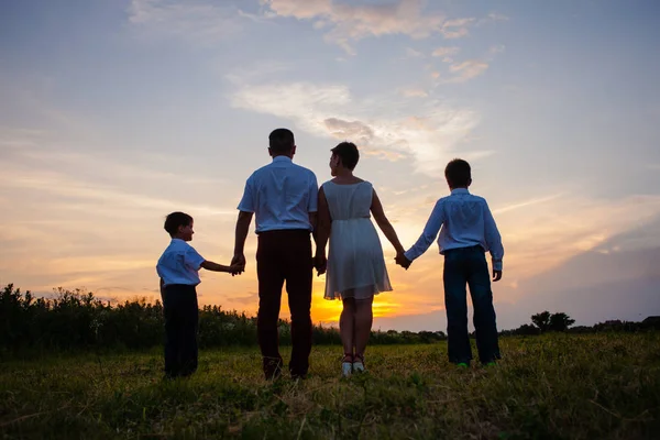 Happy family on the background of the sunset — Stock Photo, Image