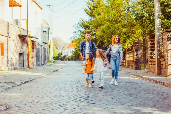 Jonge toeristen met hun dochters lopend onderaan de straat — Stockfoto