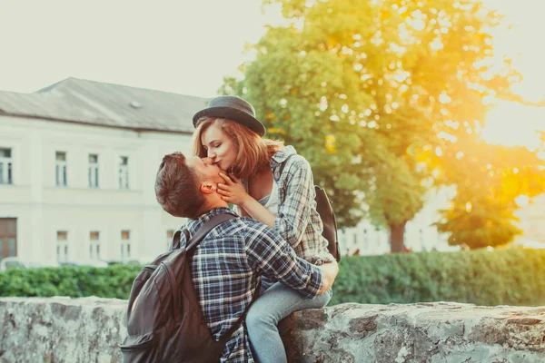 Emotional pair kissing sitting on the old stone wall — Stock Photo, Image
