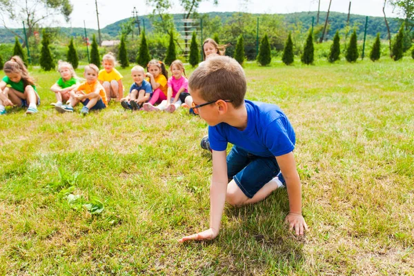 Close view of boy standing on his knees, group of kids behind him — Stock Photo, Image