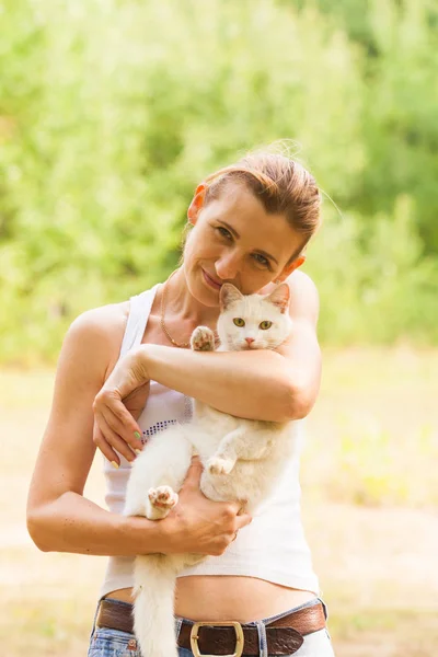 Frau hält weiße Katze im Sommerpark — Stockfoto