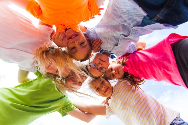 Een huddle van schoolkinderen kijken neer op de camera, — Stockfoto