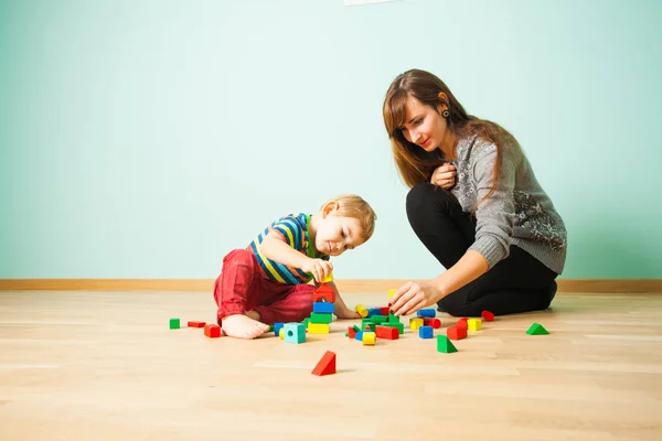 Cheerful mother playing with her kid in bedroom — Stock Photo, Image