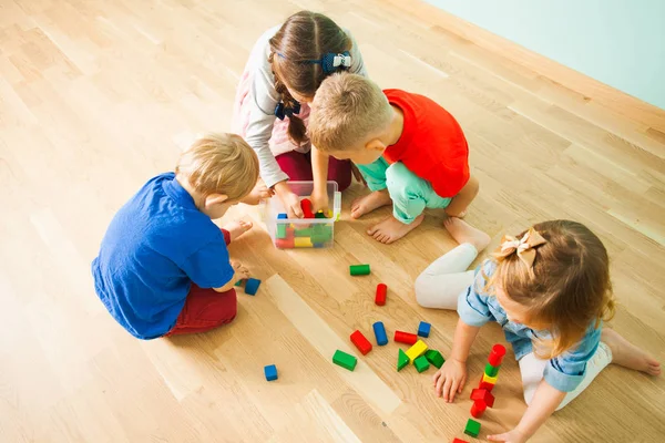 Bambini all'asilo nido che mettono i giocattoli nella scatola — Foto Stock