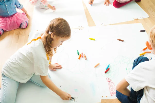 Bambini che disegnano con pastelli su un pavimento di legno — Foto Stock