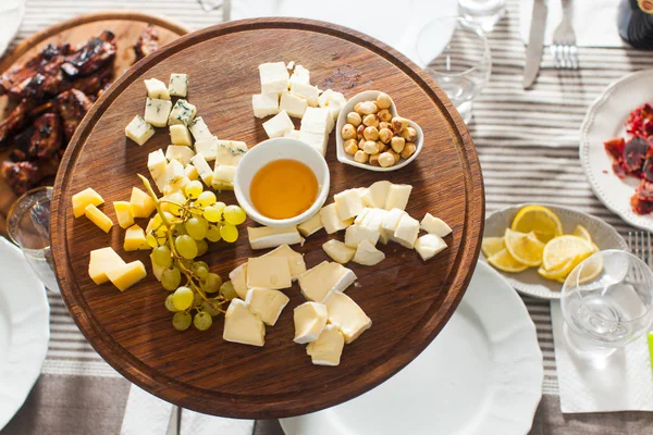 Piatto di formaggio con nocciole, miele, uva sul tavolo di legno — Foto Stock