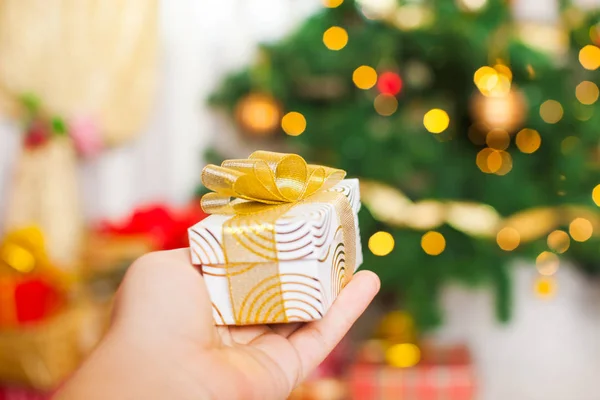 Regalo de Navidad en la mano sobre luces desenfocadas borrosas — Foto de Stock