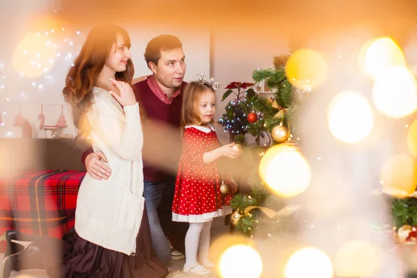 Lycklig familj med dotter dekorera julgran — Stockfoto