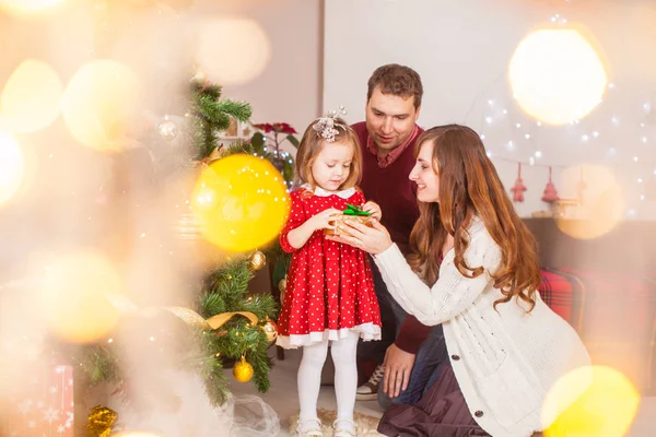 Lycklig familj med dotter öppna gåvan på julhelgen — Stockfoto