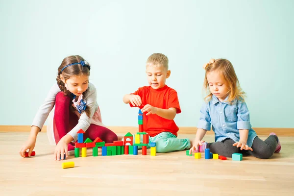 Drei Freunde bauen mit Blöcken auf einer Etage — Stockfoto