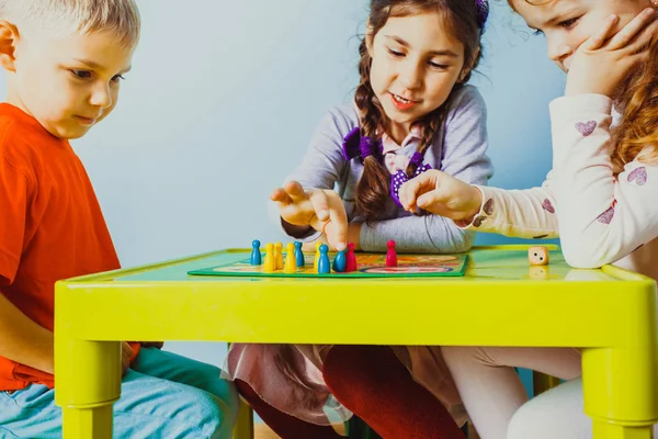 Vista da vicino delle facce dei bambini intorno al tavolo con gioco da tavolo — Foto Stock