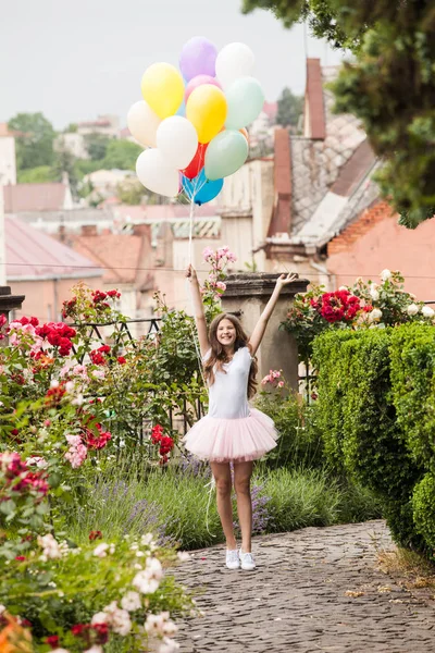 Girl with colorful latex balloons run in the park — Stock Photo, Image