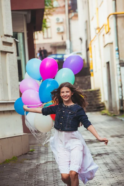 Chica con globos de colores en las calles del casco antiguo — Foto de Stock