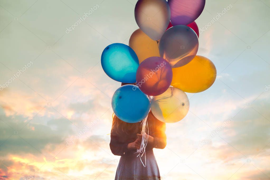 Teenage girl holds a bunch of balloons before face