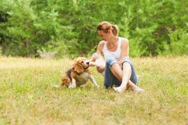 Genç kadın çimlere oturup onun Evcil hayvan ile oynarken
