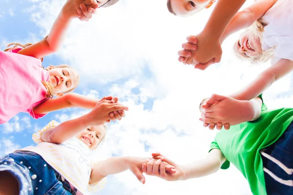 Crianças de pé em um círculo de mãos dadas, vista inferior — Fotografia de Stock