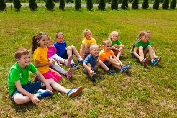 Close view of smiling kids sitting on a lawn — Stock Photo, Image