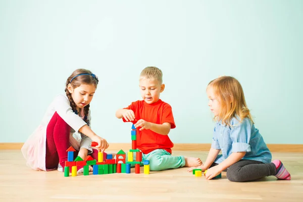 Young kids constructing towers from wooden blocks — Stock Photo, Image