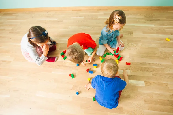 Bovenaanzicht van een groepje kinderen spelen op een vloer — Stockfoto