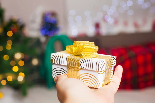 Regalo de Navidad en la mano sobre luces desenfocadas borrosas — Foto de Stock