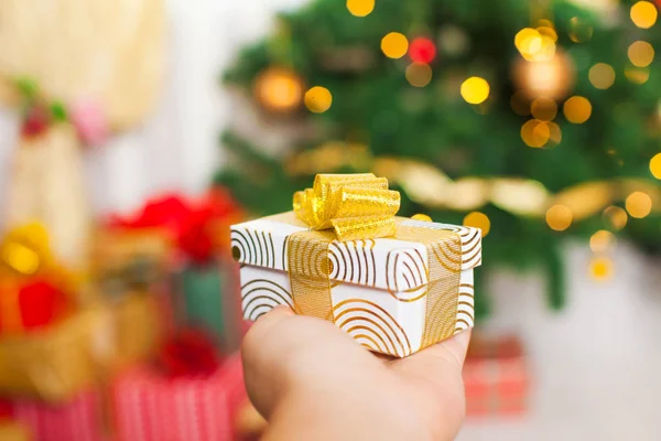 Presente de Natal na mão sobre luzes desfocadas borradas — Fotografia de Stock