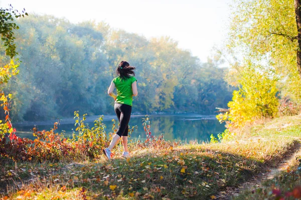 Backview of woman in motion near the forest river